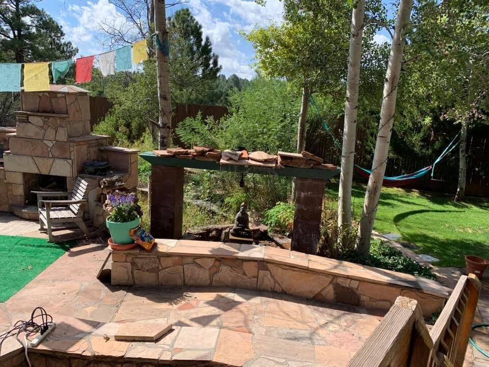 A backyard meditation garden with a torii-style gate, Tibetan prayer flags, aspen trees and a stone fireplace